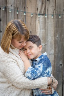 Mother and Mixed Race Son Hug Near Fence clipart