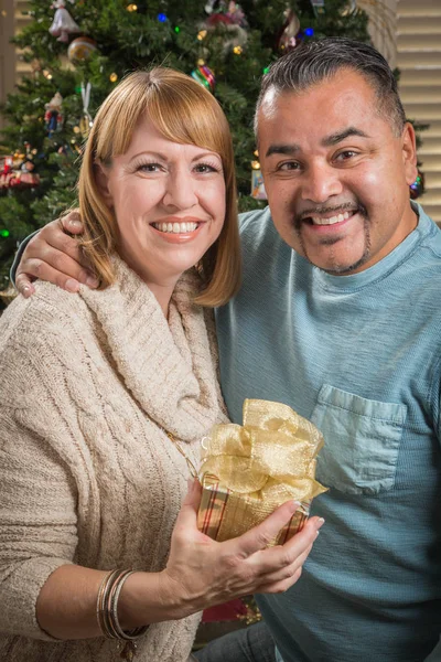 Junges Mischlingspaar mit Geschenk in der Nähe des Weihnachtsbaums — Stockfoto