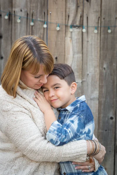 Madre e hijo de raza mixta abrazo cerca de valla —  Fotos de Stock