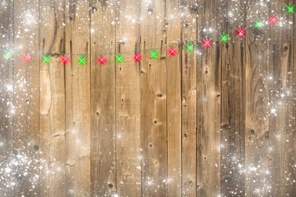 Деревянный фон с рождественскими огнями и снежной границей — стоковое фото