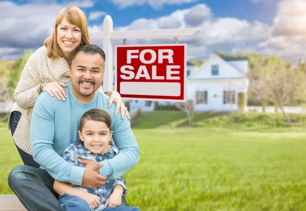 Blandad ras familjeporträtt framför huset och för försäljning fastigheter tecken — Stockfoto