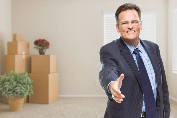 Affärsman som når för Hand skaka i rum med packade lådor — Stockfoto