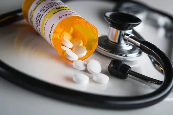 Garrafas de prescrição de medicina não proprietária e comprimidos derramados com estetoscópio — Fotografia de Stock