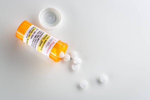 Non-Proprietary Medicine Prescription Bottle and Spilled Pills From Above on Grey