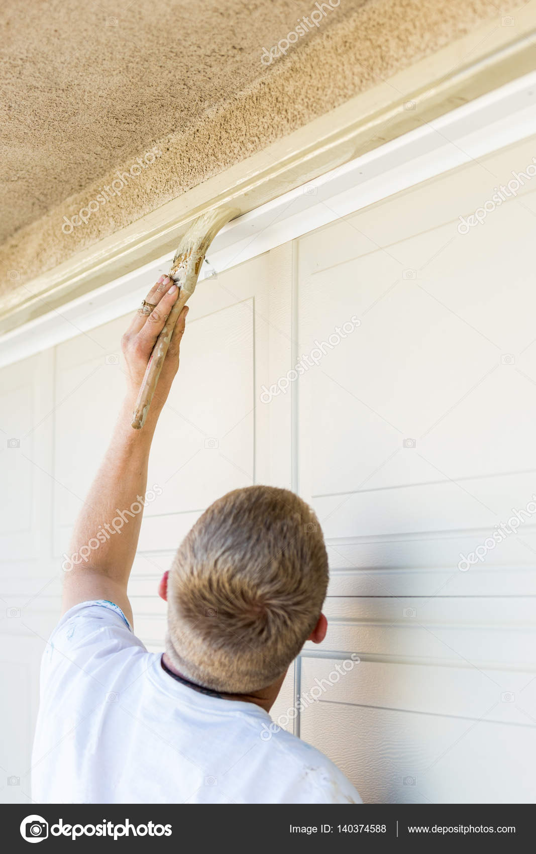 Professional Painter Cutting In With Brush To Paint Garage Door