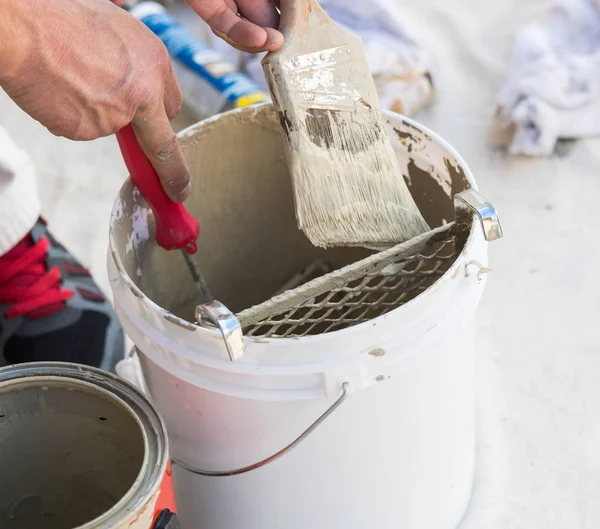 Professionele schilder laden van verf op borstel uit emmer — Stockfoto