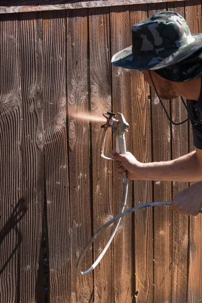 Professionele schilder sproeien van de tuin hek met vlek — Stockfoto