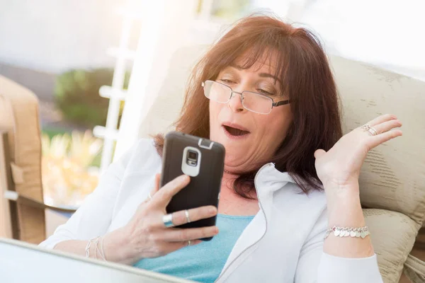 Šokovaný středního věku žena vzdechy při používání svého chytrého telefonu — Stock fotografie