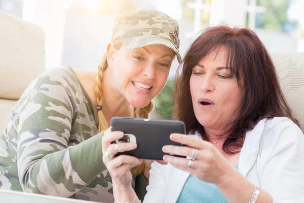 Två kvinnliga vänner skratta när du använder en Smart telefon — Stockfoto