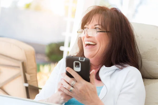 Mulher de meia-idade atraente rindo ao usar seu Phon inteligente — Fotografia de Stock