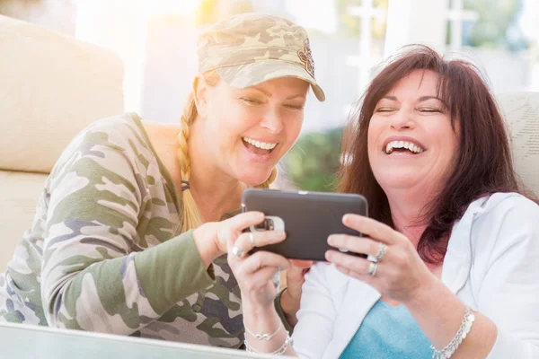 Två kvinnliga vänner skratta när du använder en Smart telefon — Stockfoto