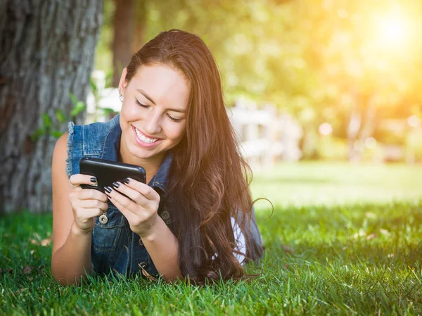 Misto raça jovem feminino texto no celular fora no grama — Fotografia de Stock