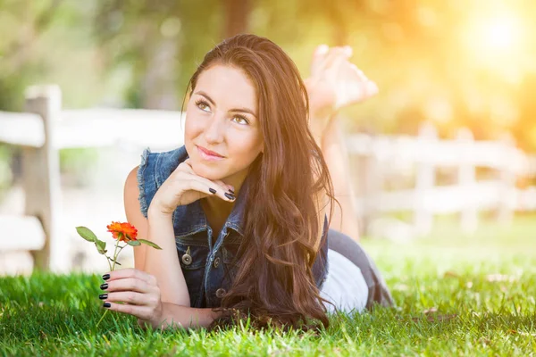 Привлекательная смешанная расовая девушка с цветочным портретом, лежащим в траве — стоковое фото