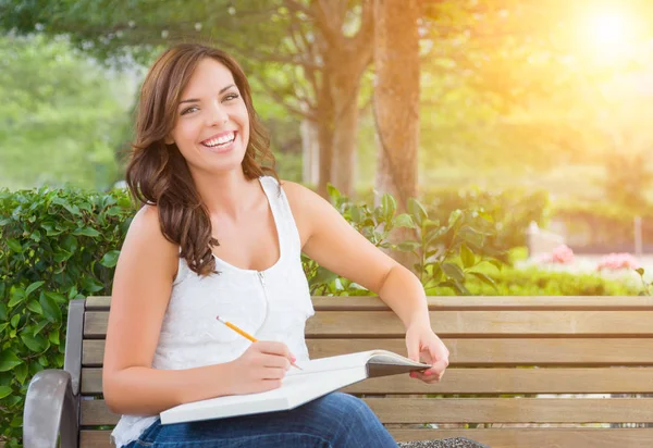 Estudiante femenina adulta joven con lápiz en el banco al aire libre — Foto de Stock