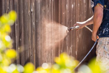 Professional Painter Spraying Yard Fence with Stain clipart