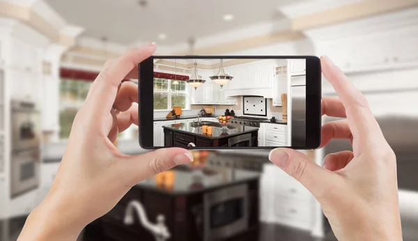 Mani femminili che tengono lo Smart Phone Visualizzazione della foto della cucina dietro — Foto Stock