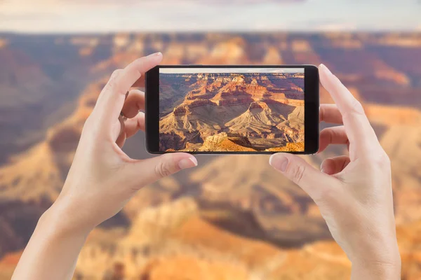 Női kéz, gazdaság intelligens telefon bemutatás fénykép mögött a Grand Canyon — Stock Fotó