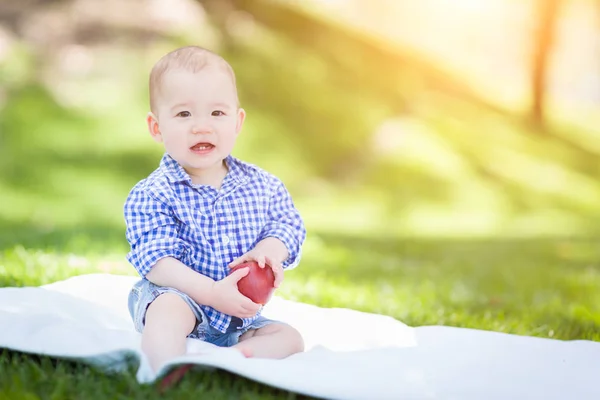 Bebé de raza mixta sentado en una manta sosteniendo salidas de manzana — Foto de Stock
