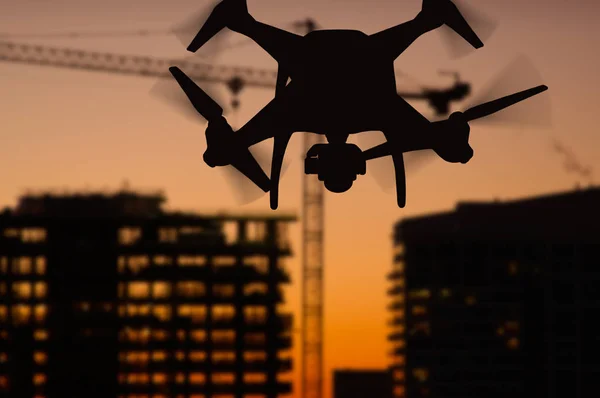 Silhueta do sistema de aeronaves não tripuladas (UAV) Quadcopter Drone no ar sobre edifícios em construção . — Fotografia de Stock
