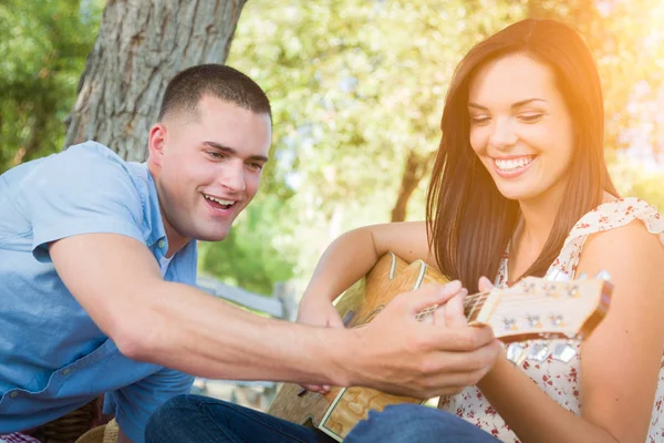 Bonito jovem ensinando menina de raça mista para tocar guitarra no th — Fotografia de Stock