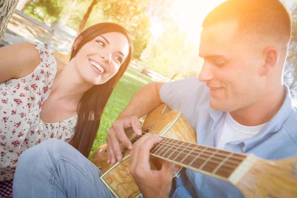 Glückliches gemischtes Rassenpaar im Park, das Gitarre spielt und singt — Stockfoto