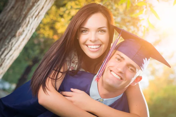 Boldog, a kupakot és a ruháját és a csinos lány férfi diplomás ünnepelni Ou — Stock Fotó