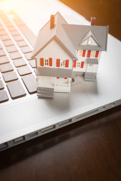 Miniature House And Laptop Computer Resting on Desktop.