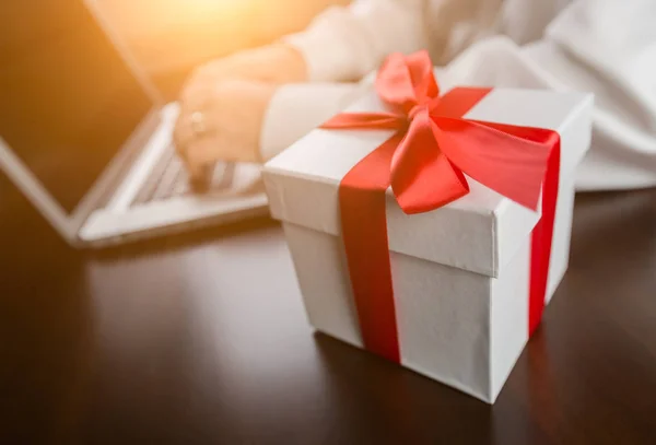 White Gift Box with Red Ribbon and Bow Near Man Typing on Laptop — Stock Photo, Image