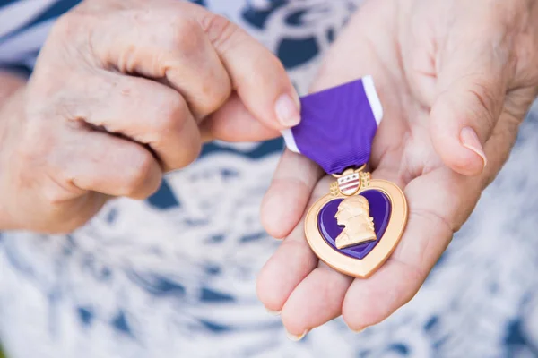 Senior Woman Holding The Military Purple Heart Medal In Her Hand — Stock Photo, Image