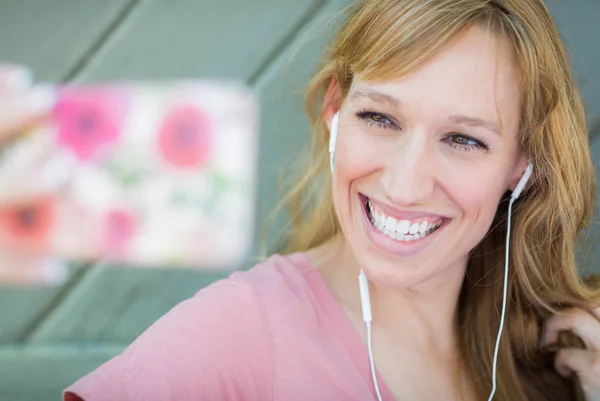 Jovem mulher adulta usando fones de ouvido tirando uma selfie com seu telefone inteligente . — Fotografia de Stock