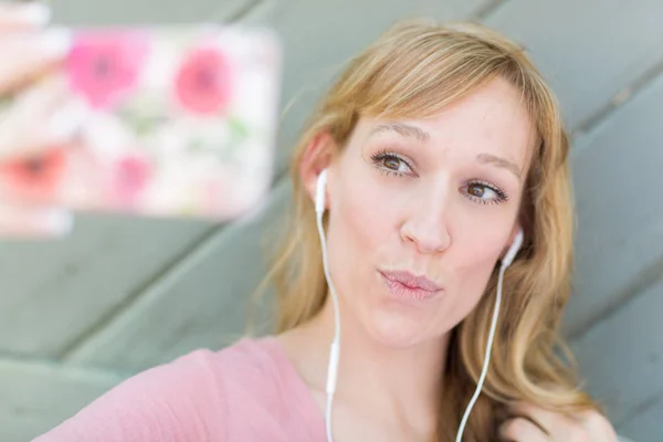 그녀의 스마트 폰으로 Selfie를 복용 하는 이어폰을 착용 하는 젊은 성인 여자. — 스톡 사진