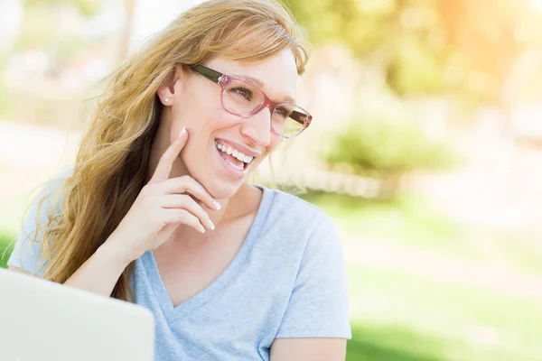 Jovem mulher adulta vestindo óculos ao ar livre usando seu laptop . — Fotografia de Stock