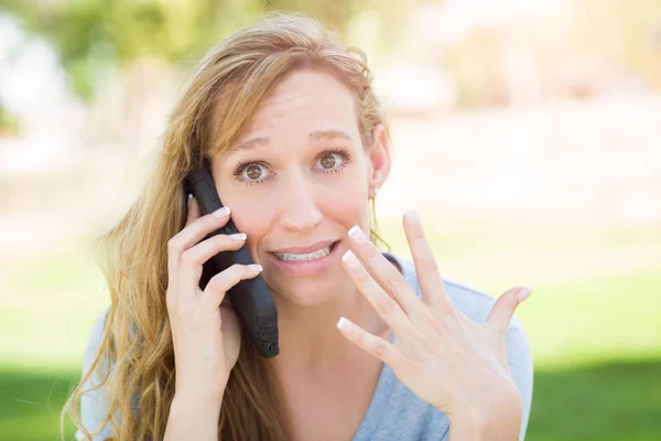 Verbijsterd jonge vrouw buitenshuis praten over haar slimme telefoon. — Stockfoto