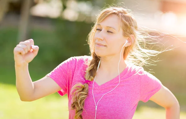 Joven mujer adulta en forma al aire libre durante el entrenamiento escuchando música — Foto de Stock