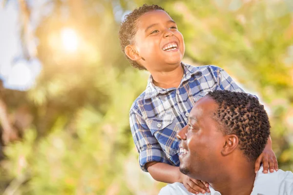 Hijo de raza mixta y padre afroamericano jugando al aire libre juntos . — Foto de Stock