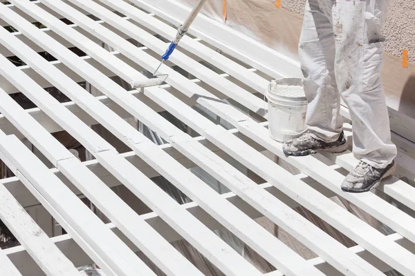 Professioneller Maler, der weiße Farbe auf die Oberseite einer Hausterrassenabdeckung rollt. — Stockfoto