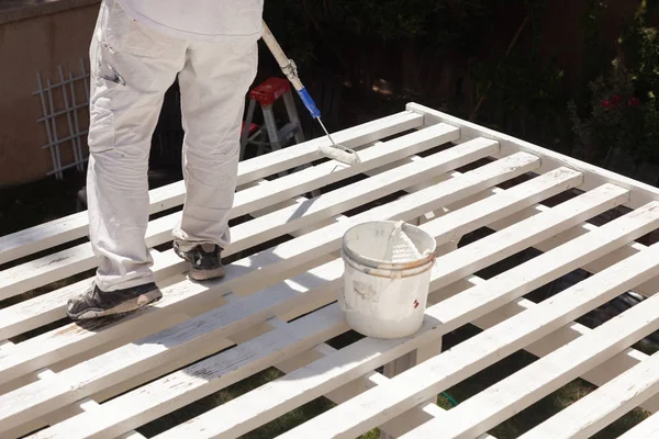 Professioneller Maler, der weiße Farbe auf die Oberseite einer Hausterrassenabdeckung rollt. — Stockfoto
