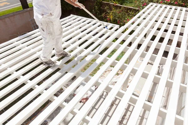 Professioneller Maler, der weiße Farbe auf die Oberseite einer Hausterrassenabdeckung rollt. — Stockfoto