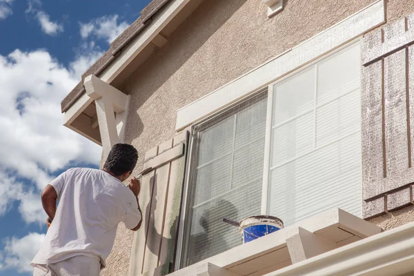 Pintor de casa profissional pintando a guarnição e as persianas de uma casa . — Fotografia de Stock