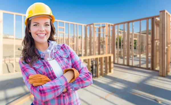 Joven atractiva trabajadora de la construcción que usa guantes, sombrero duro y gafas protectoras en el sitio de construcción . — Foto de Stock