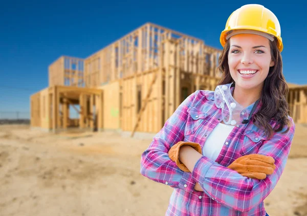 Joven atractiva trabajadora de la construcción que usa guantes, sombrero duro y gafas protectoras en el sitio de construcción . — Foto de Stock