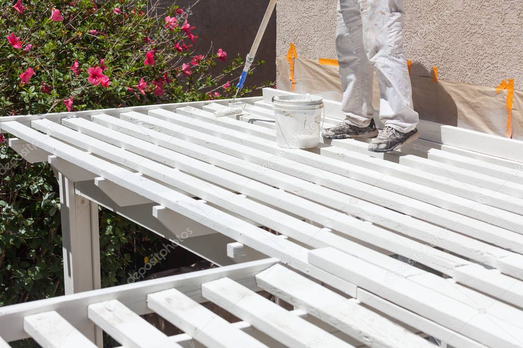 Professional Painter Rolling White Paint Onto The Top of A Home Patio Cover.