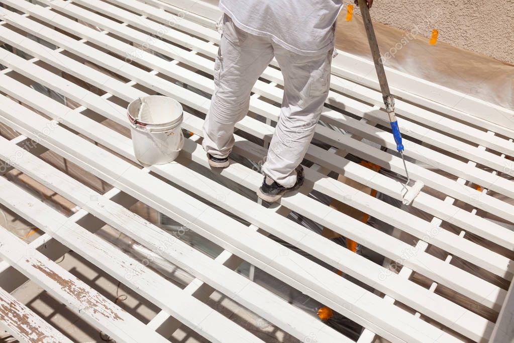 Professional Painter Rolling White Paint Onto The Top of A Home Patio Cover.