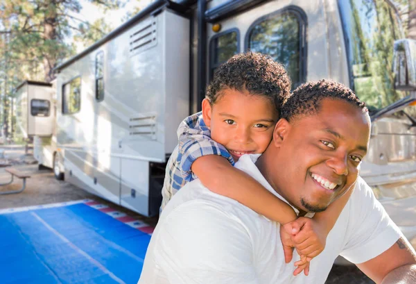 Padre afroamericano con figlio di razza mista di fronte al loro bellissimo camper al campeggio . — Foto Stock