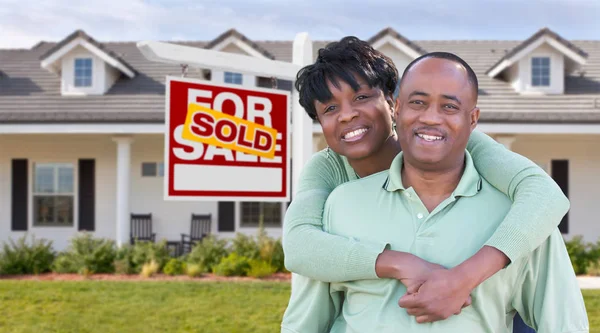 Felice afro-americano coppia di fronte a bella casa e venduto in vendita immobiliare segno . — Foto Stock