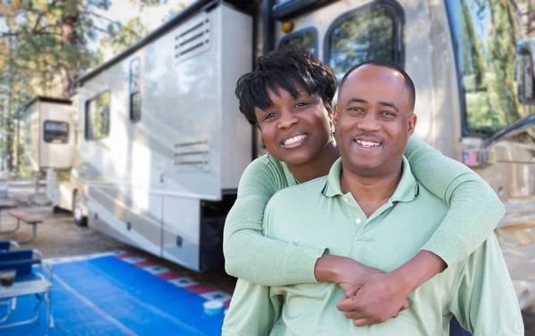 Feliz casal afro-americano na frente de sua bela caravana no acampamento . — Fotografia de Stock