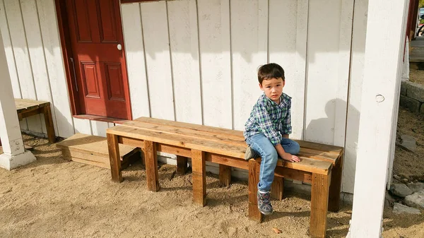 Милий молодий китайський і кавказька хлопчик, сидячи на лавці на відкритому повітрі — стокове фото