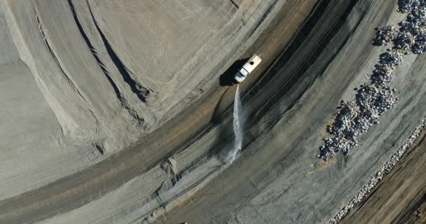 Γενικά εξαιρετικά υψηλής ευκρίνειας 4k αεροφωτογραφιών του φορτηγού νερού ποτίσματος κάτω από σωρούς των βράχων στο εργοτάξιο. — Αρχείο Βίντεο
