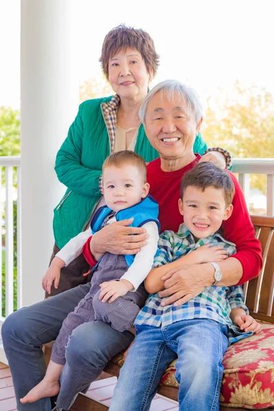 Senior erwachsenes chinesisches Paar sitzt mit seinen Enkeln der gemischten Rasse — Stockfoto