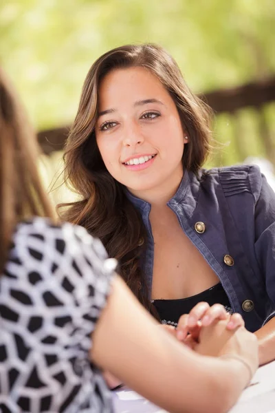 Twee vriendinnen gemengd ras een gesprek aan een tafel Outoor Patio — Stockfoto